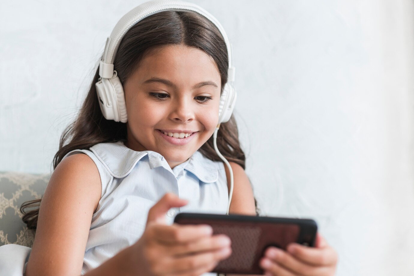 Menina sorrindo usando fones de ouvido, assistindo a um vídeo, piscando intensamente.