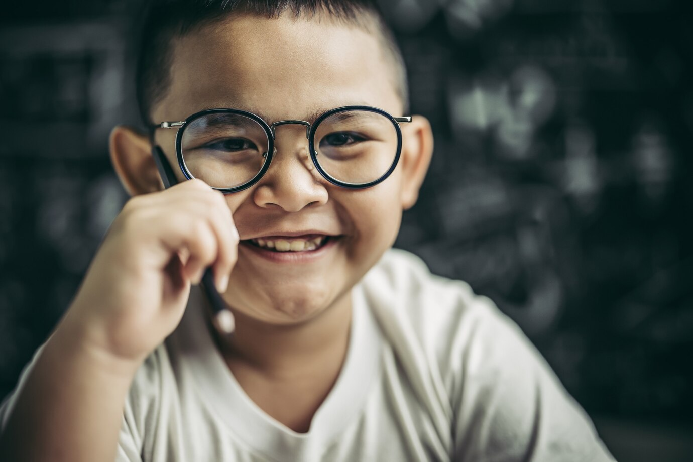 Criança sorrindo usando óculos, mostrando a importância da correção visual na ambliopia.