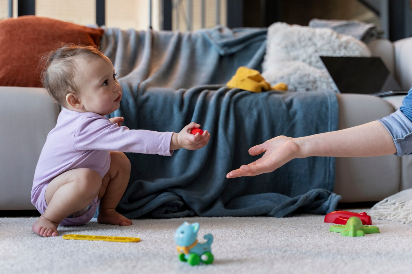 Bebê brincando no chão enquanto interage com um adulto. Palavras-chave: Estrabismo em bebê.