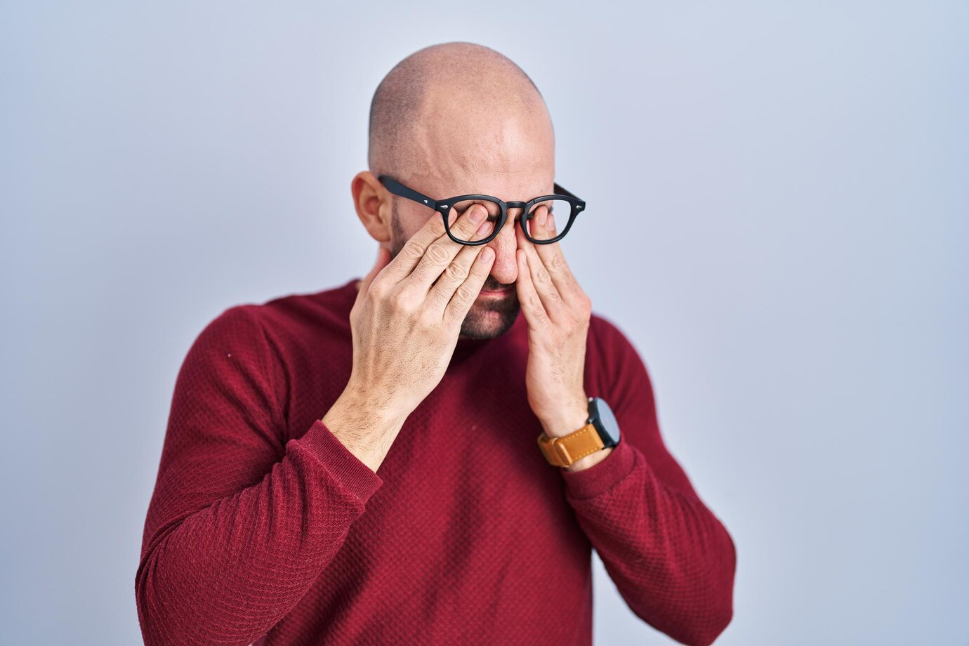 Homem de óculos massageando os olhos com expressão de desconforto diplopia.