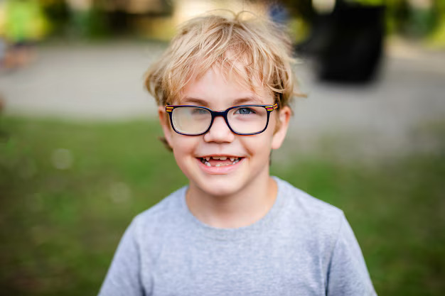 Menino sorrindo com óculos, uma lente opaca.