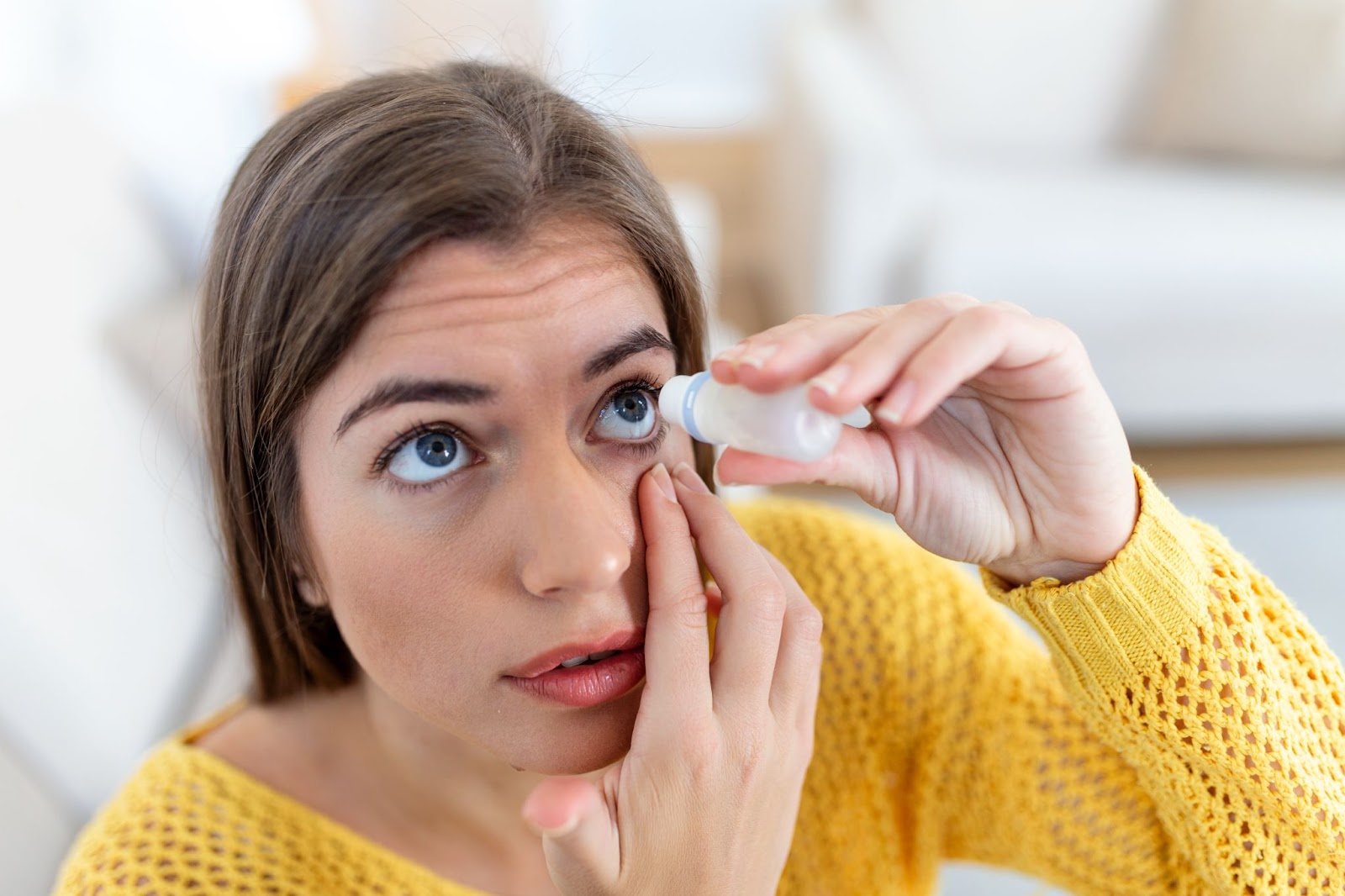 Mulher aplicando colírio nos olhos.