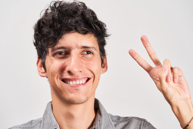 Homem sorrindo e fazendo sinal de “V” com os dedos.